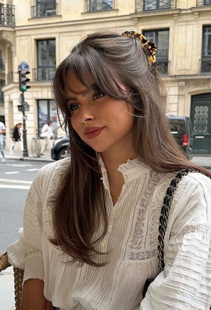 _ 27 Young woman in a white blouse with long hair, sitting at a café on a city street, looking content. | Sky Rye Design Young woman in a white blouse with long hair, sitting at a café on a city street, looking content.