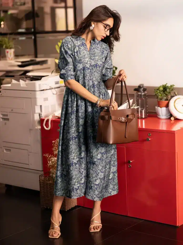 29463_2_main Woman in floral dress and glasses holds brown handbag next to office printer and red cabinet. | Sky Rye Design Woman in floral dress and glasses holds brown handbag next to office printer and red cabinet.