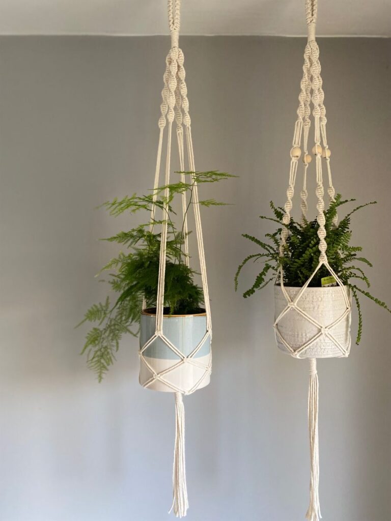2952f0a73018106a895e45bd7eda8728 Hanging macramé plant holders with green ferns against a gray wall for a boho interior decor. | Sky Rye Design Hanging macramé plant holders with green ferns against a gray wall for a boho interior decor.