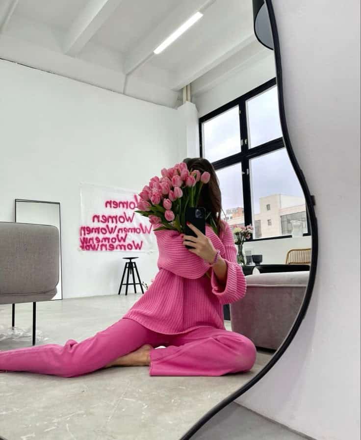 2a00973a-9880-40da-9f10-d0d237c6a0dc Woman in pink outfit takes a mirror selfie, holding a bouquet of pink tulips in a modern, bright room. | Sky Rye Design Woman in pink outfit takes a mirror selfie, holding a bouquet of pink tulips in a modern, bright room.