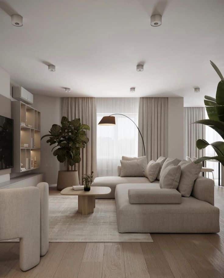 Modern living room with neutral decor, large sectional sofa, floor lamp, and indoor plants. Cozy and minimalist design.