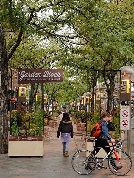 Pedestrians and cyclist at Garden Block entrance, Denver Botanic Gardens, tree-lined path with greenery.