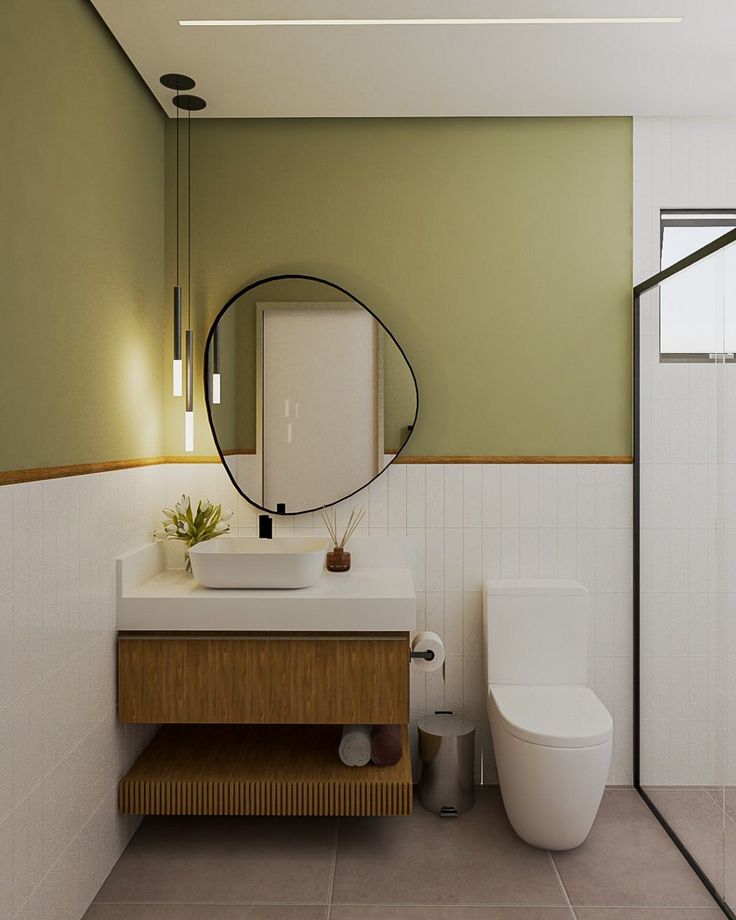 Modern bathroom with oval mirror, green wall, floating vanity, and minimalist decor.