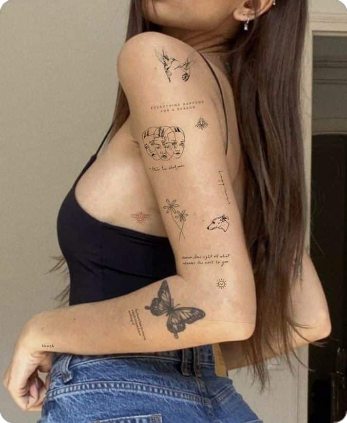 Woman with detailed arm tattoos, wearing a black top and jeans, showcasing unique artistic designs.