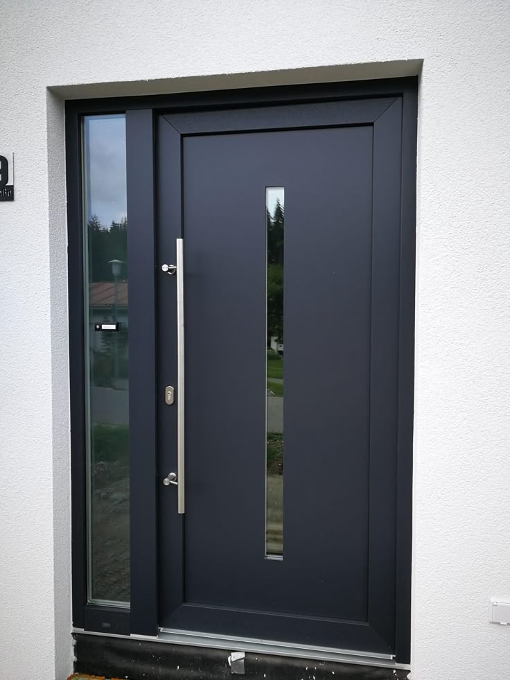 Modern black front door with vertical window and sleek silver handle.