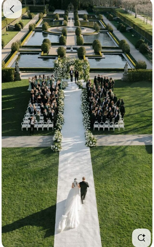 Bride walking down the aisle in a beautiful garden wedding ceremony with guests seated on both sides.