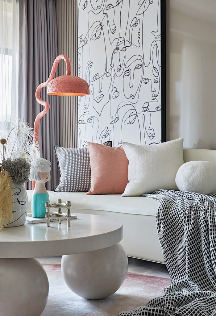 Modern living room with abstract wall art, cozy sofa, pillows, unique table, and stylish decor accents.