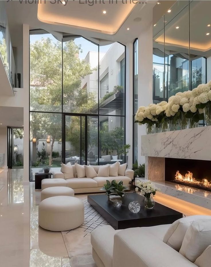 37adbb5e-5353-4c95-9618-06844b5ffeff Luxurious modern living room with high ceilings, large windows, elegant cream sofas, and a marble fireplace. | Sky Rye Design Luxurious modern living room with high ceilings, large windows, elegant cream sofas, and a marble fireplace.