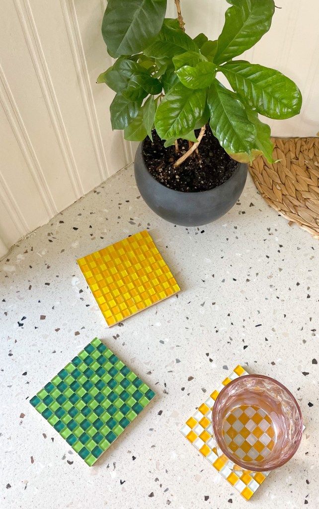 Potted plant and colorful mosaic coasters on a terrazzo floor enhance cozy home decor vibes.