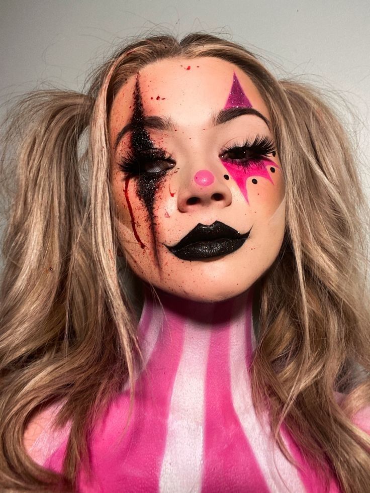 Person with dramatic pink and black clown makeup, black lips, and striped body paint. Halloween or cosplay theme.