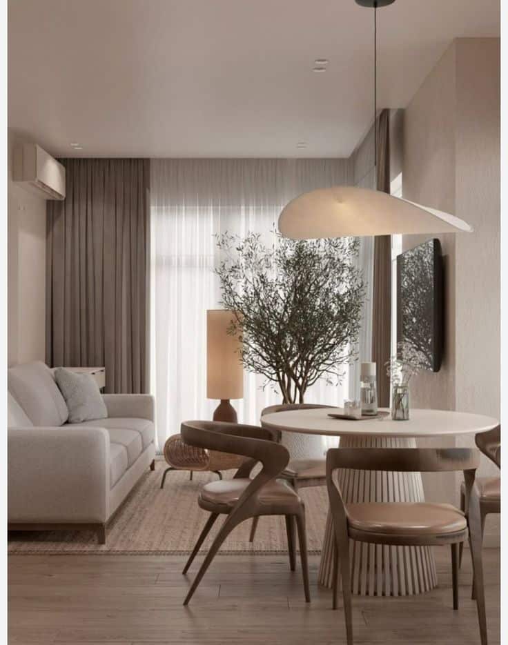 Modern living room with a cozy sofa, round dining table, stylish chairs, and indoor plant under soft ambient lighting.