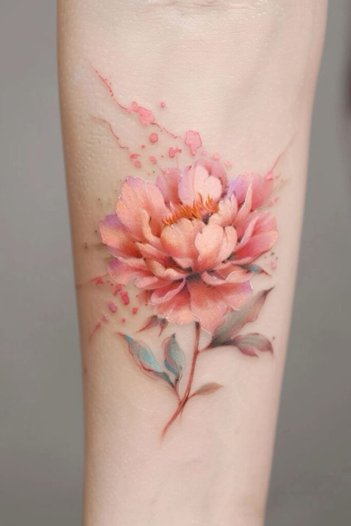 Delicate watercolor-style pink peony tattoo on forearm with splashes of color and realistic details.