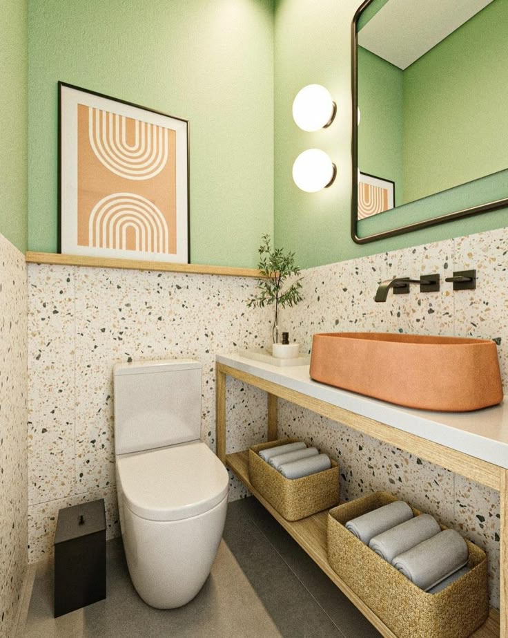Modern bathroom with green walls, terrazzo tiles, sleek fixtures, and woven baskets for storage.