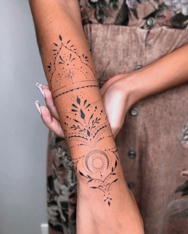Intricate black geometric floral tattoo design on forearm, showcasing elegant line and dot patterns.