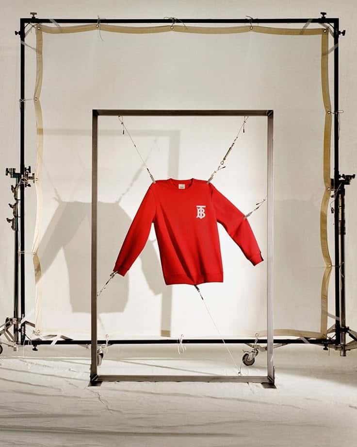 _ 4 Red sweatshirt with TB logo suspended in metal frame, studio setup. | Sky Rye Design Red sweatshirt with TB logo suspended in metal frame, studio setup.