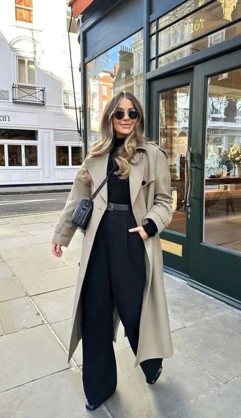 Stylish woman in a beige trench coat and sunglasses walking on a city street, showcasing chic autumn fashion.