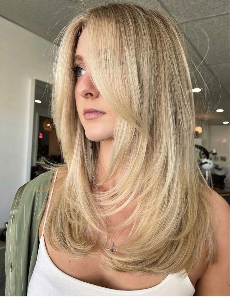 Woman with long layered blonde hair in modern salon setting.