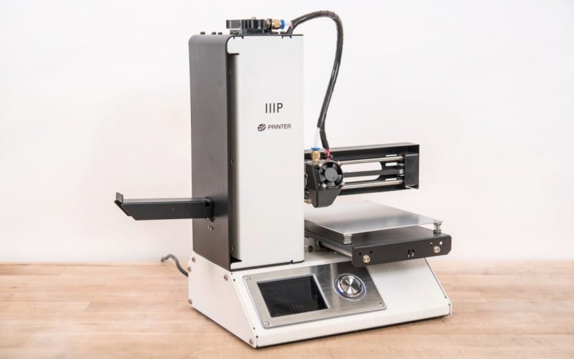 Compact 3D printer on a wooden surface, ready for desktop additive manufacturing projects.