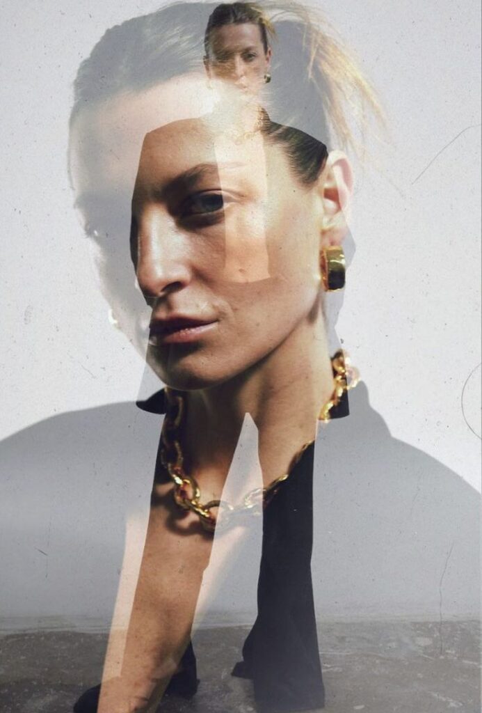 Double exposure portrait of a woman with bold jewelry and confident expression, creating an artistic visual effect.