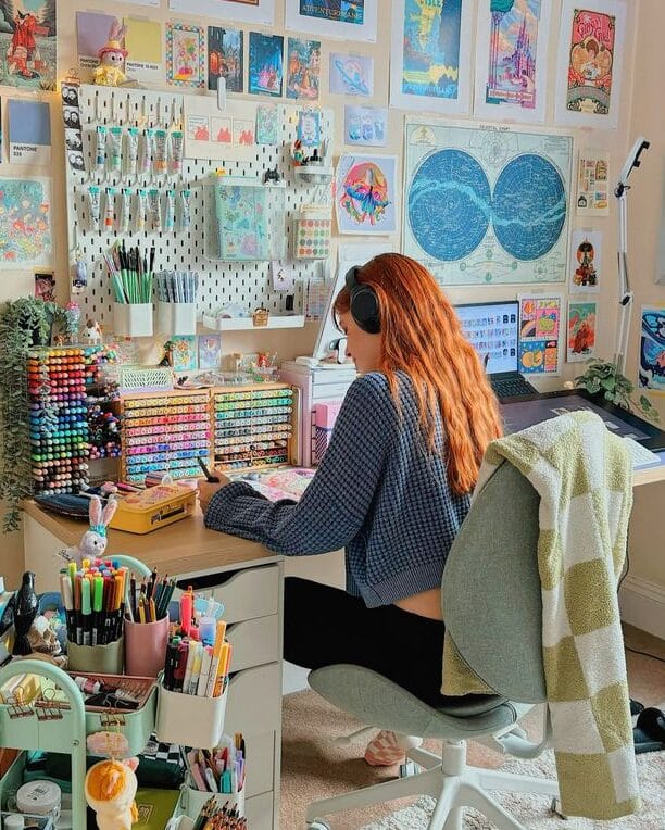 Artist working in a colorful, organized studio with art supplies and inspiring wall decor.