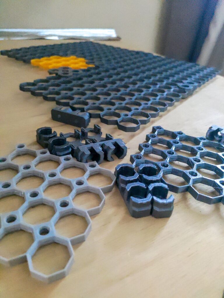 Hexagonal table mat with 3D-printed design pieces on a wooden surface.