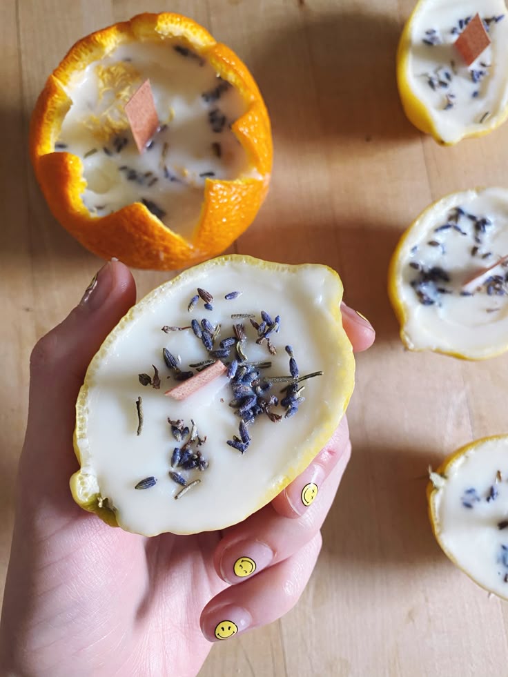 DIY citrus candle with lavender and wooden wick held in hand, surrounded by more handmade candles on a wooden surface.