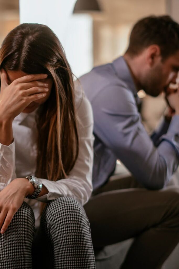 Two people sitting back-to-back, looking upset, reflecting relationship conflict or disagreement.
