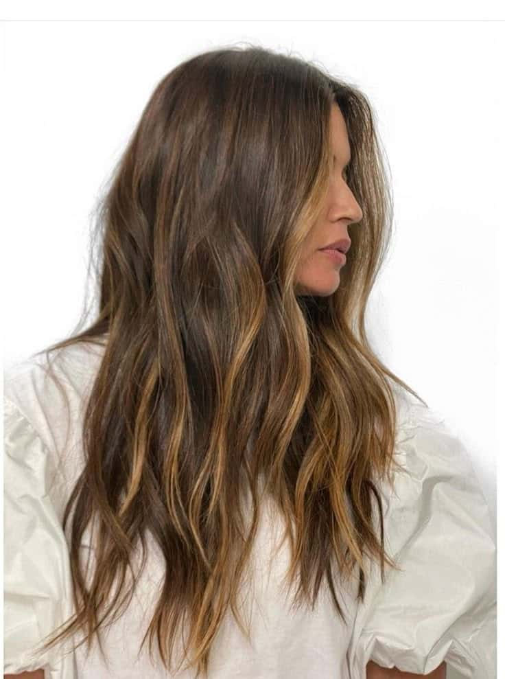 _ 5 Brunette woman with wavy hair and subtle highlights in white top, side view. Elegant hairstyle inspiration. | Sky Rye Design Brunette woman with wavy hair and subtle highlights in white top, side view. Elegant hairstyle inspiration.