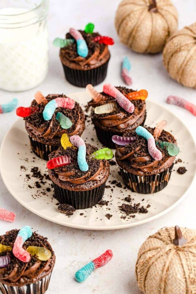 _ 5 Chocolate cupcakes topped with gummy worms and cookie crumbs on a plate, perfect for Halloween treats. | Sky Rye Design Chocolate cupcakes topped with gummy worms and cookie crumbs on a plate, perfect for Halloween treats.