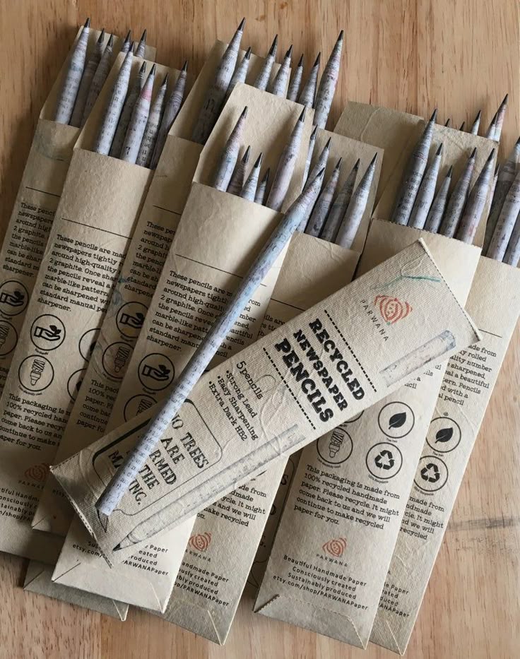 Recycled newspaper pencils in eco-friendly packaging on a wooden table. Sustainable and environmentally conscious stationery.
