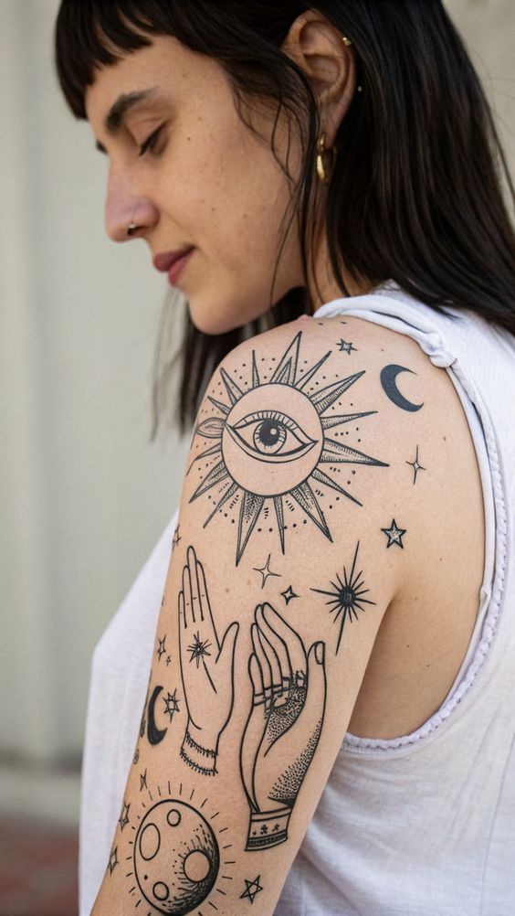 Woman with mystical tattoos featuring sun, moon, hands, and stars on arm, wearing sleeveless white shirt.