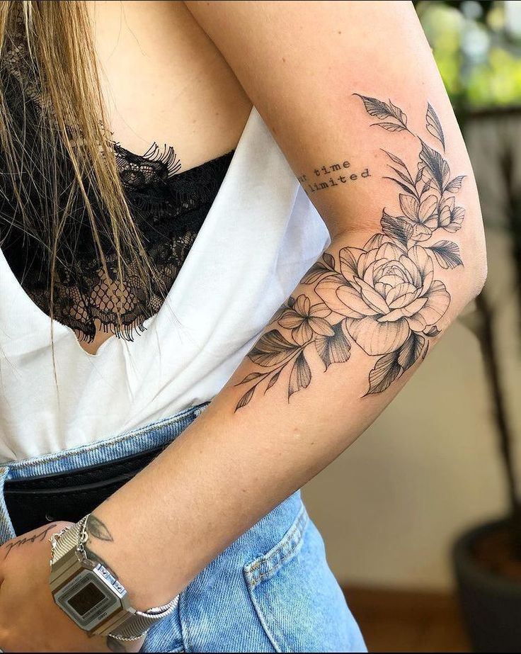 Arm tattoo featuring detailed floral design with phrase, denim shorts, and lace-trimmed top.