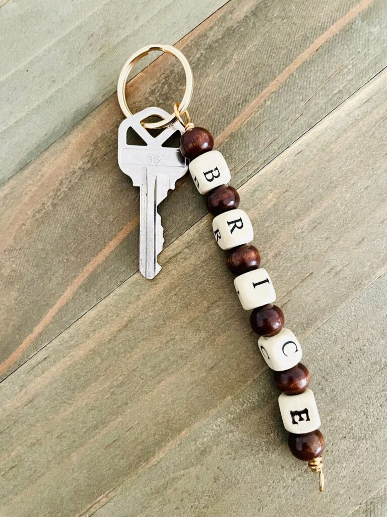 Key with custom name bead keychain on a wooden surface.