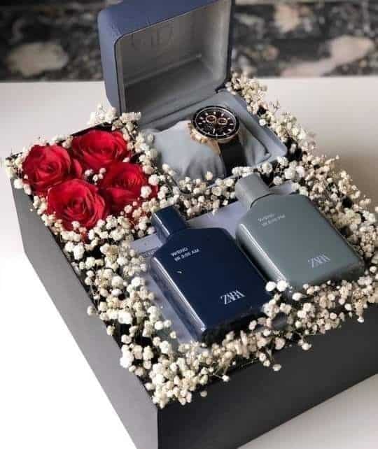 Gift box with a luxury watch, two Zara perfumes, red roses, and delicate white flowers. Perfect for special occasions.
