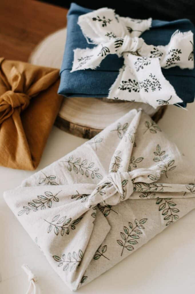 Eco-friendly fabric-wrapped gifts with leaf patterns and rustic charm on a wooden surface.