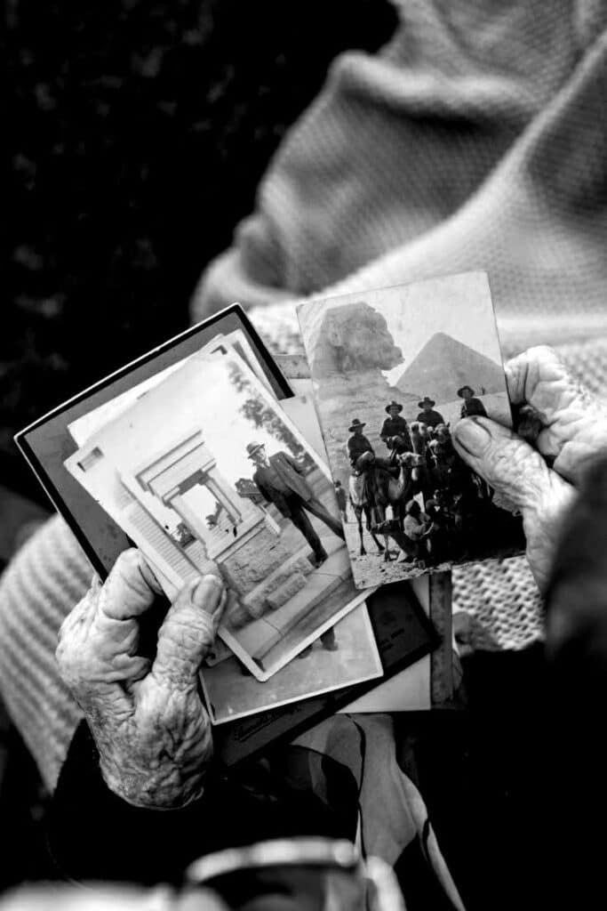 Elderly hands holding vintage black and white photographs, evoking nostalgia and memories of past adventures.