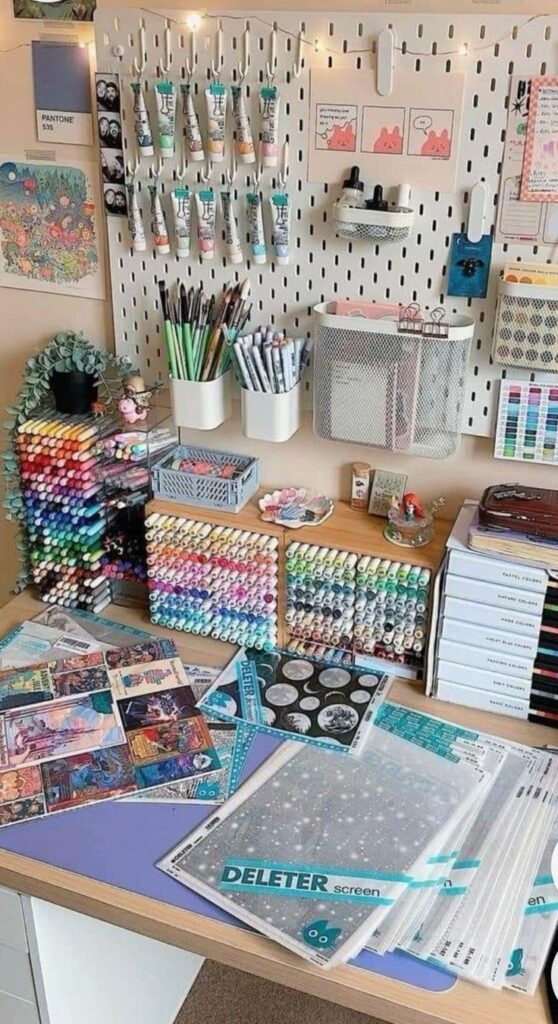 Organized art supplies display with markers, paints, and sketch pads on a desk and pegboard.