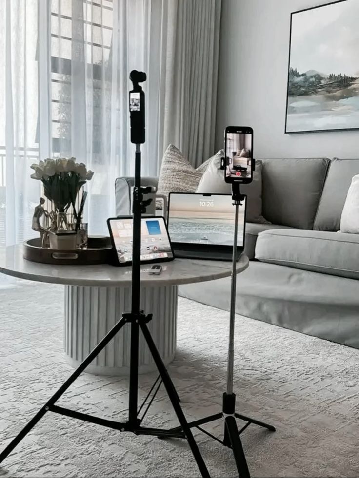 Cozy living room setup with tech gadgets on a table, including tablets and a smartphone on tripods for content creation.