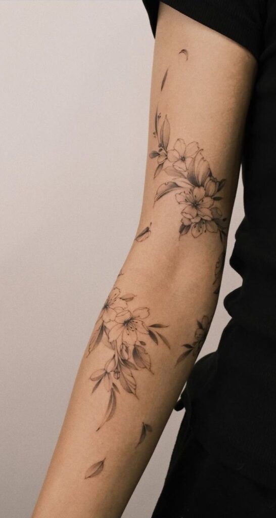 Floral arm tattoo in black ink featuring delicate blossoms and leaves.