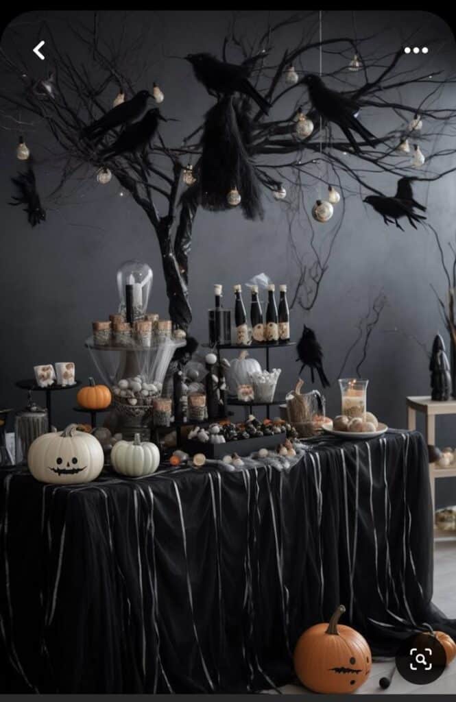 Spooky Halloween table with black crows, pumpkins, and dark decor for a festive party setting.
