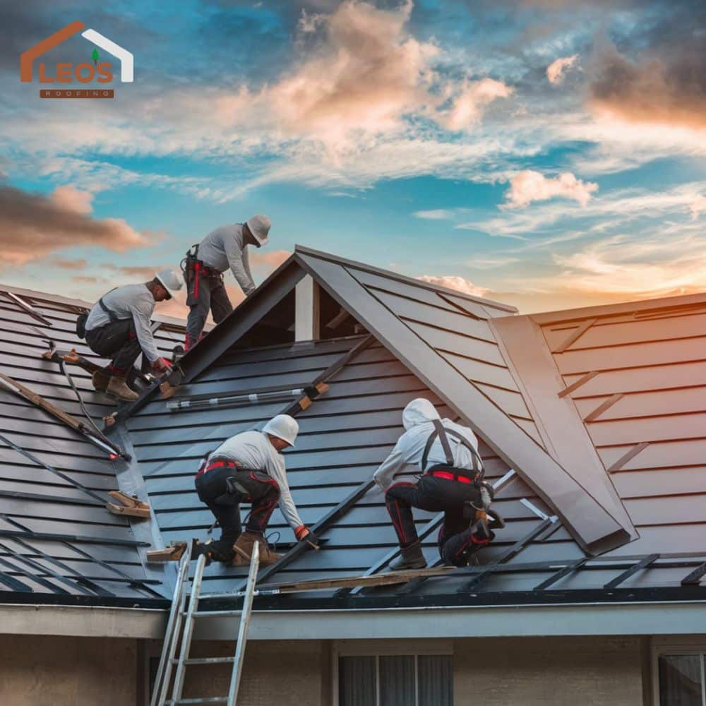 Roofers installing metal roofing at sunset, showcasing craftsmanship and teamwork.