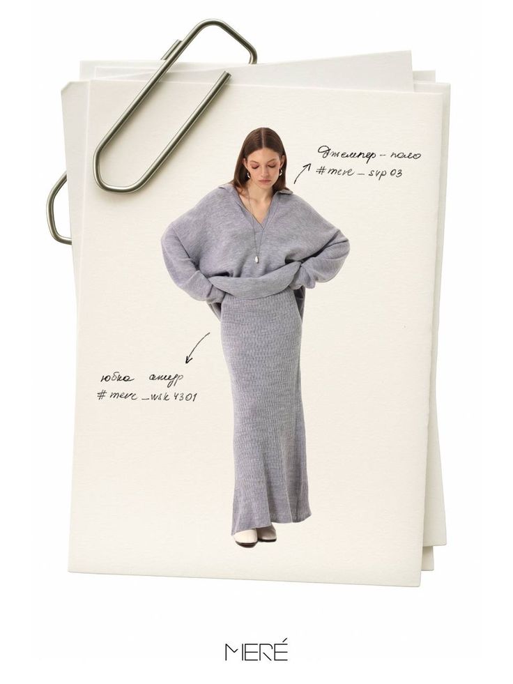 Woman in a stylish gray sweater and long skirt ensemble, with oversized paperclip accents.