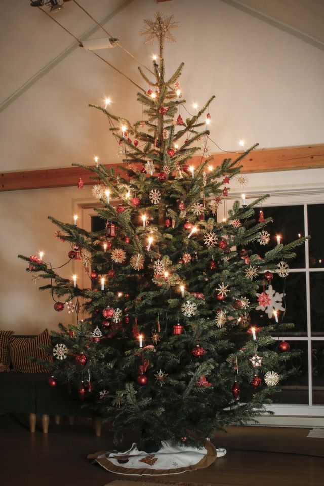 Decorated Christmas tree with lights, red ornaments, and snowflake decorations in a cozy living room setting.