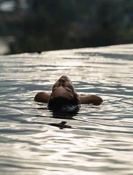 Person peacefully floating on water surface, enjoying a moment of relaxation with serene surroundings.