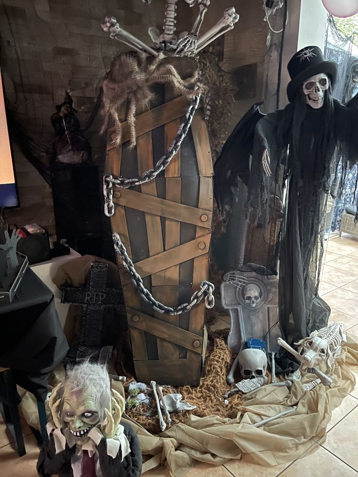 Spooky Halloween scene with a coffin, skeletons, and grim reaper decorations on display.