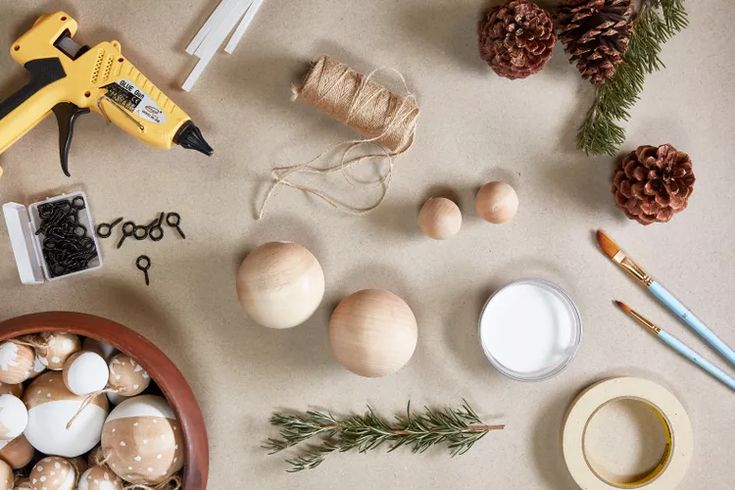 71 Unique DIY Christmas Ornaments to Personalize Your Tree This Year Craft supplies for DIY holiday ornaments: glue gun, twine, pinecones, paintbrushes, wood balls, and rosemary sprigs. | Sky Rye Design Craft supplies for DIY holiday ornaments: glue gun, twine, pinecones, paintbrushes, wood balls, and rosemary sprigs.