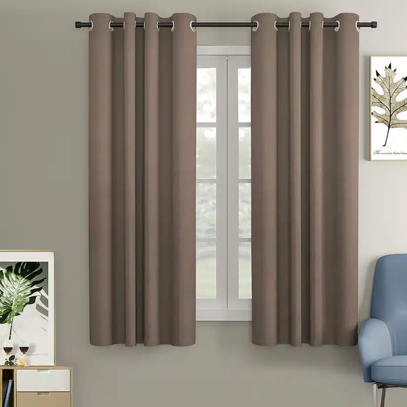 Modern brown curtains on a window with wall art, enhancing a cozy living room with a blue chair.