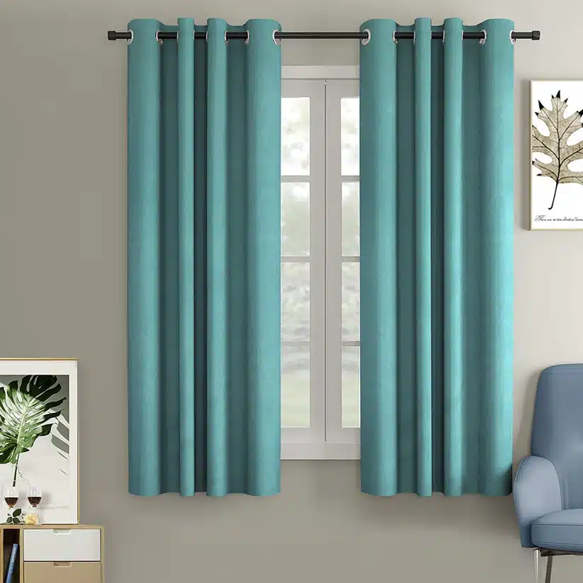 Teal curtains hanging on a window with wall decor and furniture, providing a modern and cozy room atmosphere.
