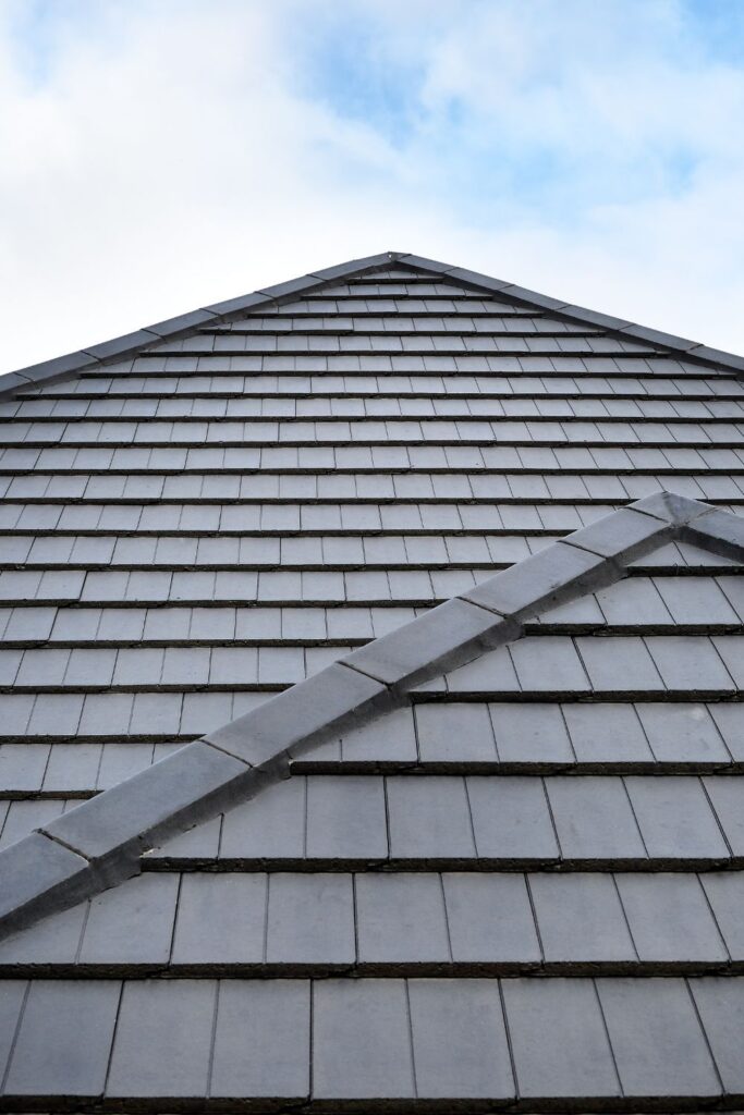 Close-up of gray slate roof tiles against a blue sky, showcasing durable and modern construction.
