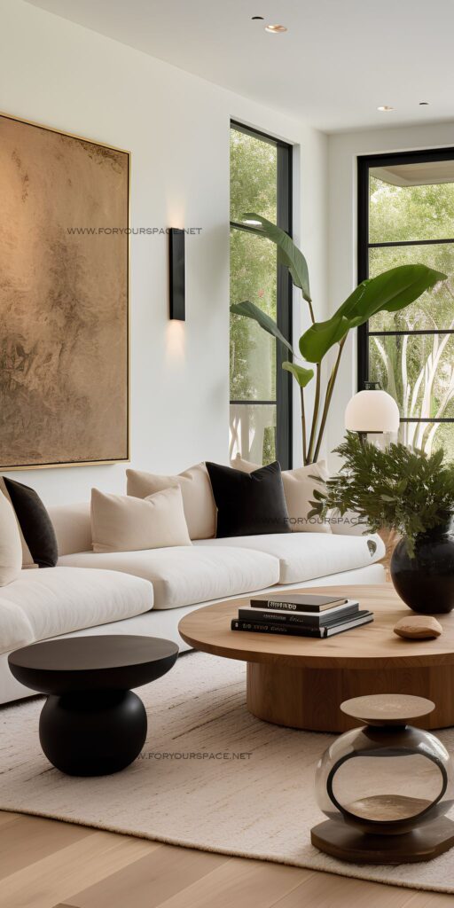 Modern living room with white sofa, black pillows, abstract art, and plants, showcasing minimalist interior design.